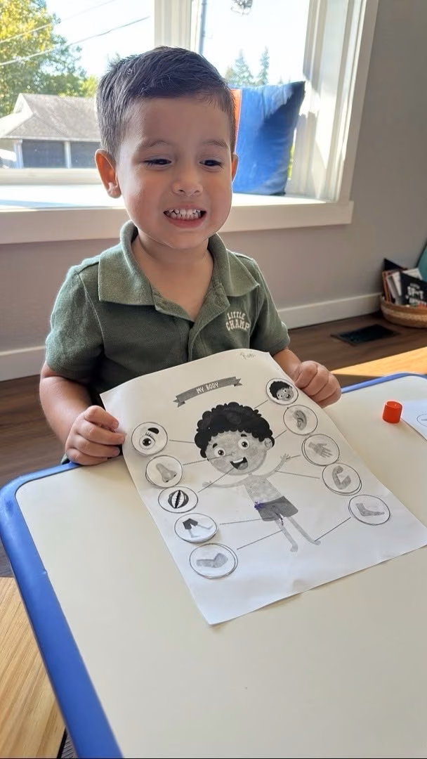 Niño mostrando su trabajo en la mesa de actividades