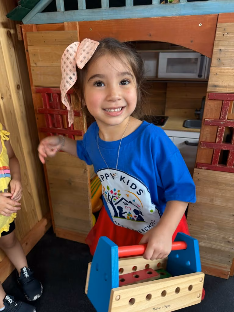 Niña jugando en la casita de madera del patio